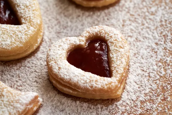 Kalp şeklinde ev yapımı Linzer Noel kurabiyesi. Kırmızı çilek reçeli ve şekerle doldurulmuş.