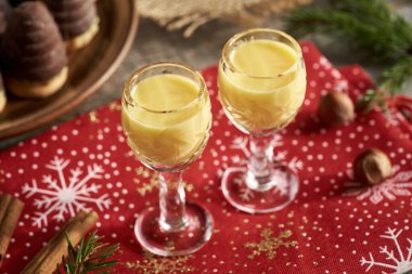 İki bardak eggnog, eşekarısı yuvası ya da arı kovanlı. Arka planda Çek Noel kurabiyeleri.