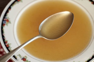 Çorba kasesinin üstündeki metal kaşıkta tavuk kemiği çorbası.