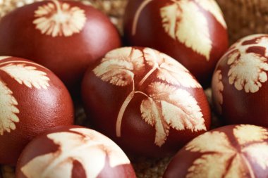 Kahverengi Paskalya yumurtalarının yakın çekimleri soğan kabuklarıyla boyanmış ve bitki yaprakları ile boyanmış.
