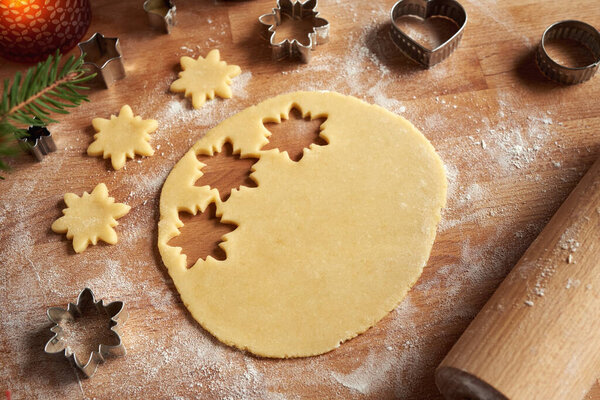 Pastry dough with cut out star shapes on a rolling board - preparation of Linzer Christmas cookies