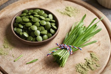 Kuru toz ve tabletlerle taze yeşil arpa yaprakları.