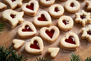 Kalp şeklinde Linzer Noel kurabiyeleri çilek reçeli ile doldurulmuş, şekerle tozlanmış, yakın plan.