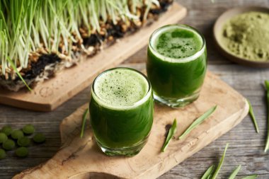 İki bardakta yeşil arpa otu suyu, taze yetişmiş bıçaklarla.
