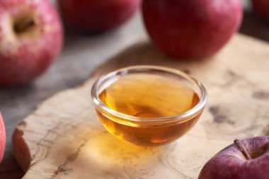 Bir kase elma sirkesi ve masada taze meyve.