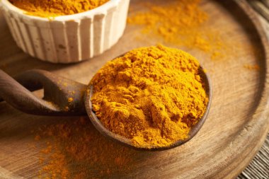 Masadaki tahta kaşıkta kurumuş zerdeçal kökü tozu.