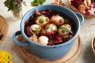 Paskalya yumurtalarını taze yapraklarla boyayarak soğan kabuklarını tencereye koyuyorlar.