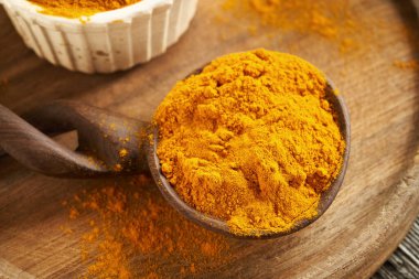 Tahta bir masada kaşığın üzerinde zemin zerdeçal kökü.