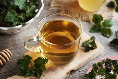 Masada taze ısırgan otu olan bir fincan bitki çayı.