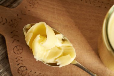 Ahşap bir masada kaşıkta açık bir tereyağı.