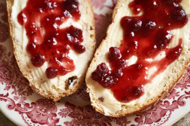 Kırmızı tabakta tereyağı ve kızılcık reçelli mazanec denilen geleneksel Çek tatlı paskalya pastasından iki dilim.