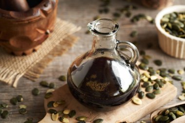 Tahta bir masada cam sürahide işlenmemiş kabak tohumu yağı.