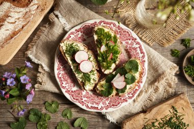 Yaban mersinli bitkiler - soğan otu, sarımsaklı hardal ve toprak büyüğü, bir tabak ekmeğin üzerinde.