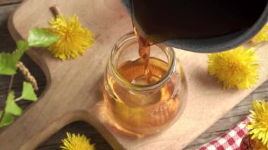 Sıcak ev yapımı karahindiba balı - taze Taraxacum çiçeklerinden yapılan bitkisel şurup - cam kavanozlara dökülüyor