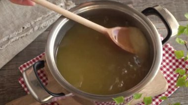Karahindiba şurubu veya bal hazırlama - taze karahindiba çiçeklerinin eritildiği suda karıştırıcı şeker