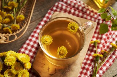 Taze tay çiçeği ve yapraklı bir fincan bitki çayı.