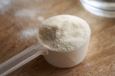 Tahta bir masada plastik bir kaşık içindeki kolajen tozu.