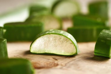 Masadaki ahşap kesme tahtasının üzerinde taze bir parça aloe vera yaprağı.