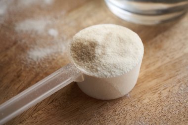 Masadaki plastik bir kaşık içindeki kolajen tozu.