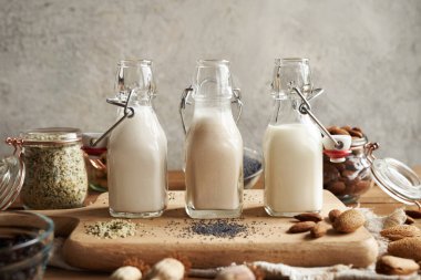 Üç cam şişe içinde haşhaş tohumu, haşhaş tohumu ve bademlerden yapılmış vejetaryen fındık sütleri.