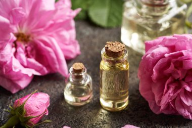 Aromaterapi şişeleri koyu arkaplanda pembe Provence çiçekleri olan gerekli yağ.