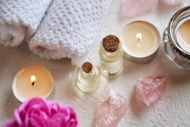 Gül kuvars taşları, gül çiçekleri ve beyaz arka planda spa havluları olan aromaterapi şişeleri.