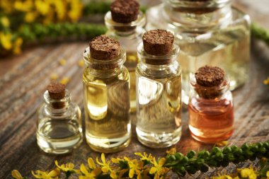 Bir şişe aromaterapi, taze tarımsal yağ ya da masa üzerinde yaprak otu çiçekleri.