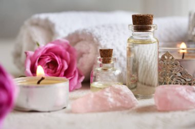 İki şişe aromaterapi esaslı yağ gül de Mai çiçekleri, gül kuvars taşları ve beyaz spa havluları.