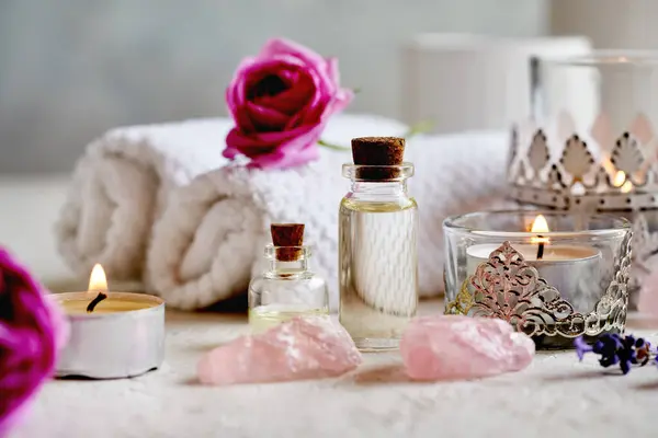 stock image Bottles of aromatherapy essential oil with lavender and rose de Provence flowers, rose quartz stones and spa towels on white background