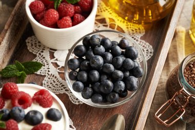 Bir kasede taze yabanmersini, keten tohumu, ahududu ve arka planda süzme peynir.