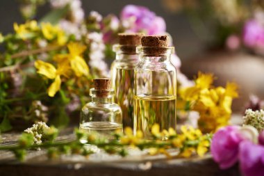 Masanın üzerinde renkli yaz çiçekleri olan aromaterapi şişeleri.