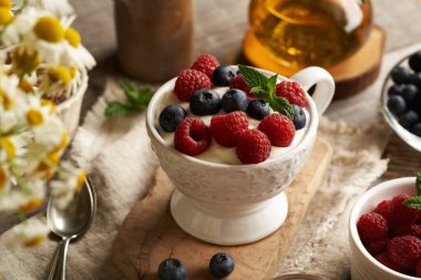 Keten tohumu yağıyla harmanlanmış süzme peynir taze ahududu ve yaban mersiniyle dolu bir kasede beyaz bir kapta.