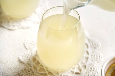 Beyaz bir masada cam bir fincana taze süt döküyorum.