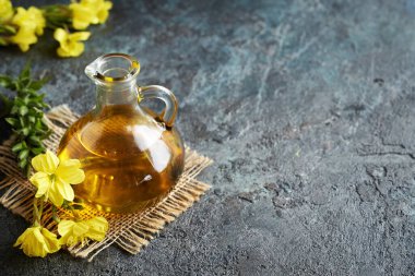 Koyu arkaplanda cam bir sürahi içinde akşam çiçeği yağı ve fotokopi alanı.