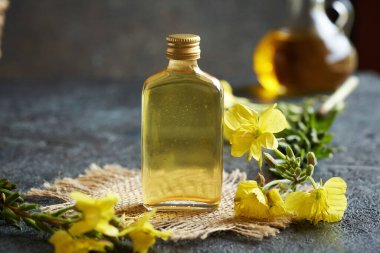 Koyu arkaplanda cam bir şişede çuha çiçeği yağı.