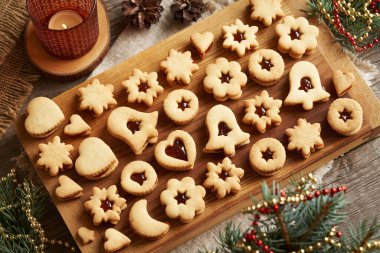 Ahşap bir masada çilek reçeli ile doldurulmuş ev yapımı Linzer Noel kurabiyeleri.
