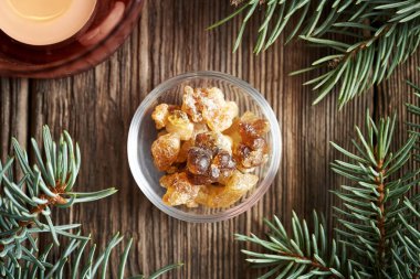 Tütsü reçinesi bir kâse içinde ladin ağacı dalları ve Noel 'de mum.