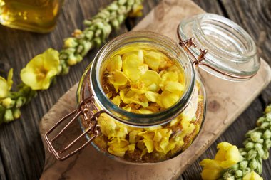 Taze Mullein veya Verbascum çiçeklerinden elde edilen ev yapımı bitkisel şurup ve cam kavanozdaki şeker.