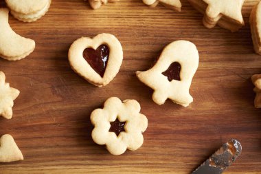 Üç Linzer Noel kurabiyesi. Çilek reçeli. Tahta üzerinde, üst manzara.