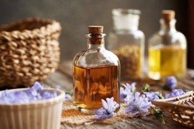 Şeffaf cam bir şişe bitkisel tentür ve taze hindiba çiçekleri