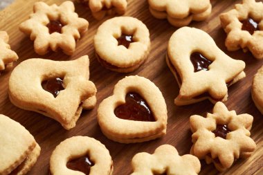 Kalp, yıldız ve çan şeklinde kırmızı marmelatla doldurulmuş Linzer Noel kurabiyeleri.