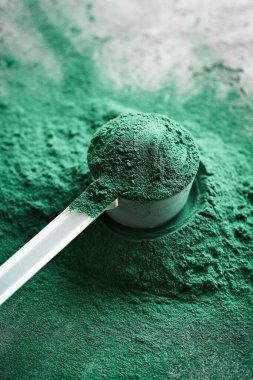 Plastik ölçü kabında yeşil spirulina yosun tozu - sağlıklı besin takviyesi