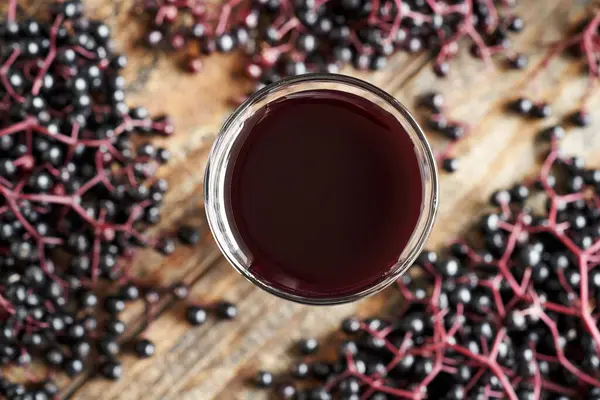 stock image A glass of black elder syrup for immunity with fresh elderberries, top view