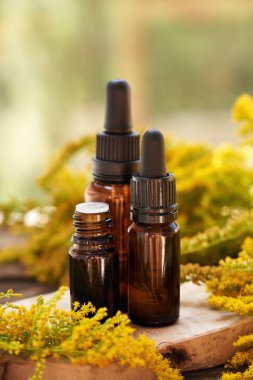 Siyah aromaterapi şişeleri altın çubuklu gerekli yağ ya da masada Solidago kanadensis çiçekleri