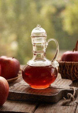 Bir şişe elma sirkesi ve açık havada taze meyve.