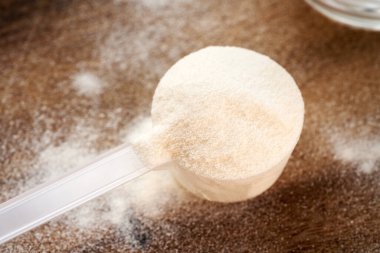 Tahta bir masada plastik bir kepçenin içindeki kolajen tozu.