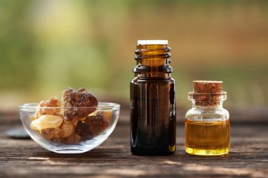 Tütsü şişeleri Boswellia reçineli yeşil bokeh ile açık bir masada gerekli yağ