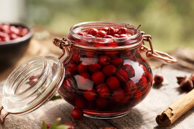 Macerating fresh hawthorn berries in red wine in a glass jar - preparation of medicinal drink clipart