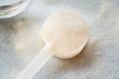 Plastik bir kepçeyle kolajen tozu, yakın çekim.