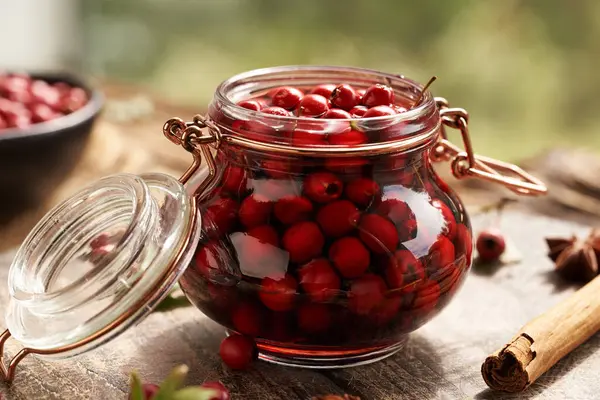 stock image Macerating fresh hawthorn berries in red wine in a glass jar - preparation of medicinal drink